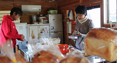 焼きあがったパンの袋詰めと値付け作業をしている松下さんご夫婦の写真