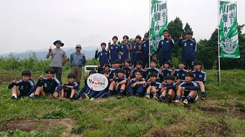 ジャージを着た26人の選手と二人の男性が外で並んで記念撮影をしている写真