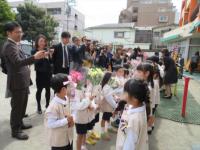 アルストロメリアの花束をプレゼントされた園児たちとその様子をそばで見ている保護者の写真
