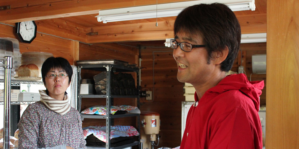 パンの調理場に立っている松下さんご夫婦の写真