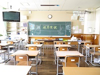 机と椅子が並ぶ中、2年4組学級目標境界突破の文字と教室の前面をイラストにした黒板を、教壇側から撮影した写真