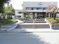 晴れた日に撮られた、数段の階段と上部に時計のある学校の正面玄関の写真