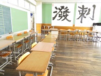 L字型に2列に並べられた机・椅子と、撥刺と習字で書かれた大きな紙が奥の壁に貼られている写真